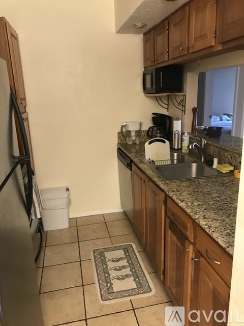 A kitchen with a granite counter top and wooden cabinets.