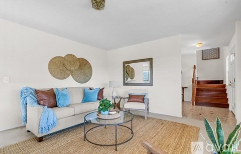 A living room with a white couch, a coffee table, and a painting on the wall.