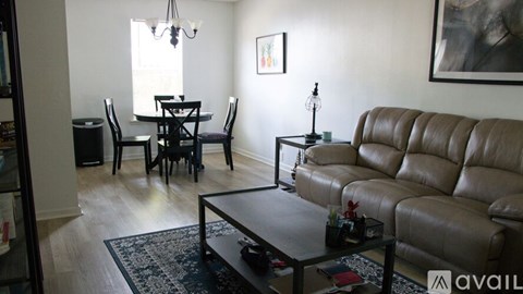 A living room with a brown leather couch and a black dining table.