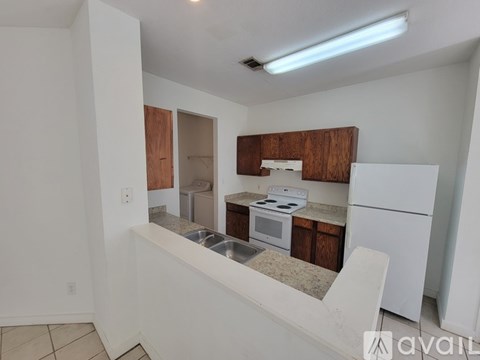 A kitchen with white appliances and wooden cabinets is available for rent.