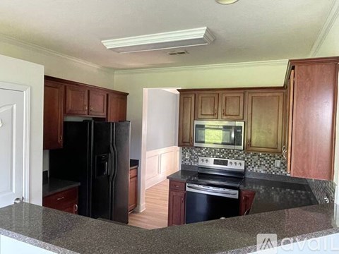 A kitchen with a black refrigerator and stove top oven.