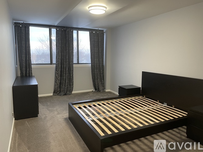 A bedroom with a large bed and a window with curtains.