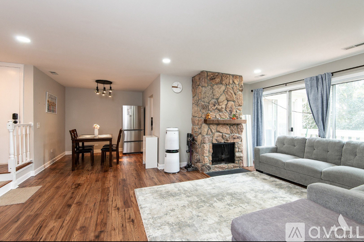 A living room with a stone fireplace and a grey couch.