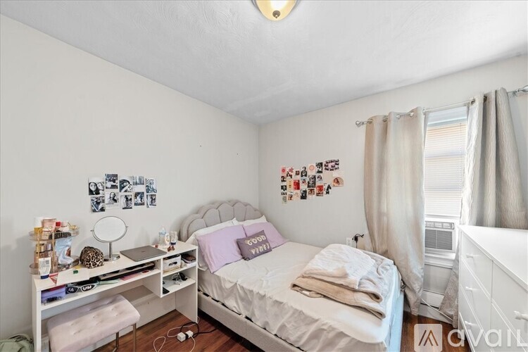 A bedroom with a bed, nightstand, and a wall of pictures.