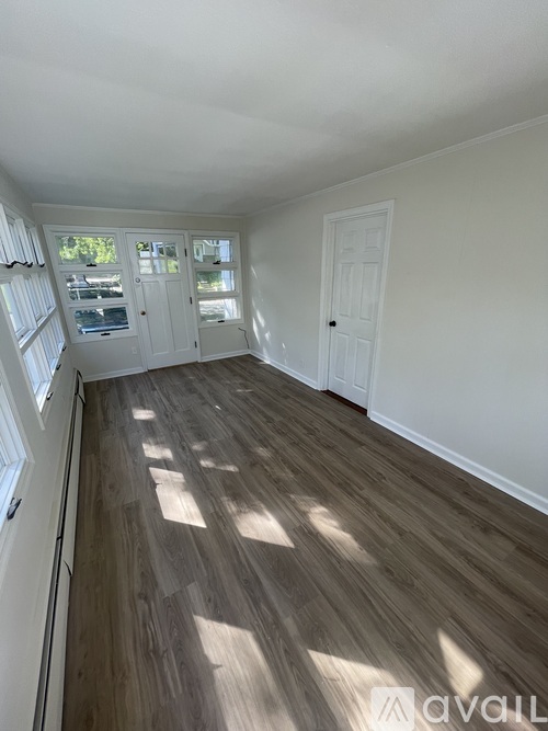 A room with wooden flooring and white walls.