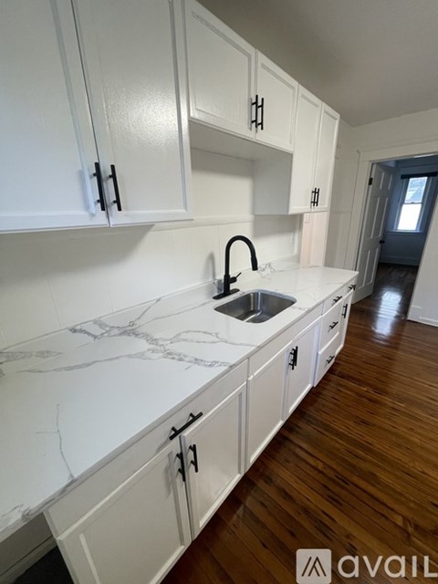 A kitchen with white cabinets and a marble countertop.