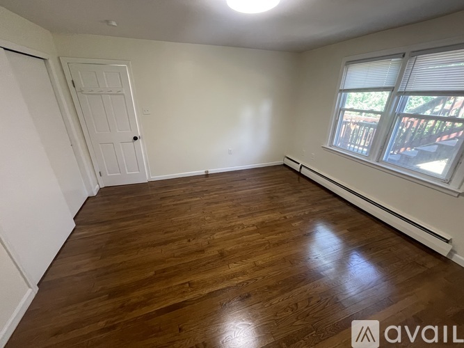 A room with wooden flooring and a window with blinds.