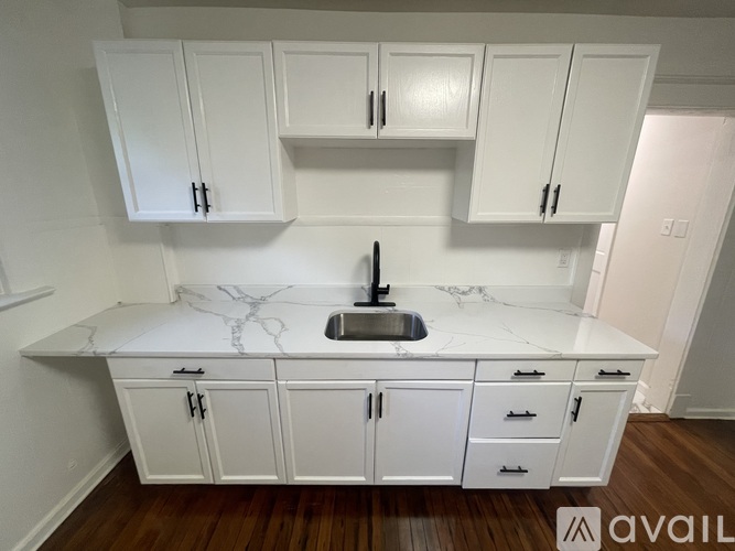 A kitchen with white cabinets and a marble countertop.