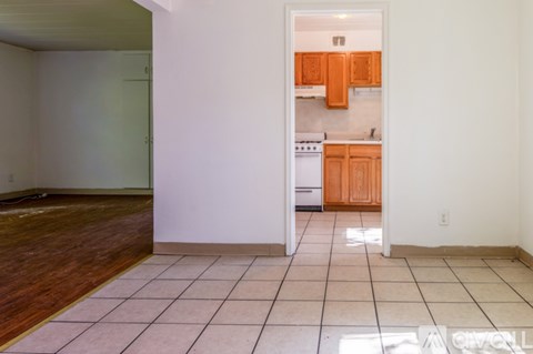 A kitchen with wooden cabinets and a white dishwasher is visible through an open door.