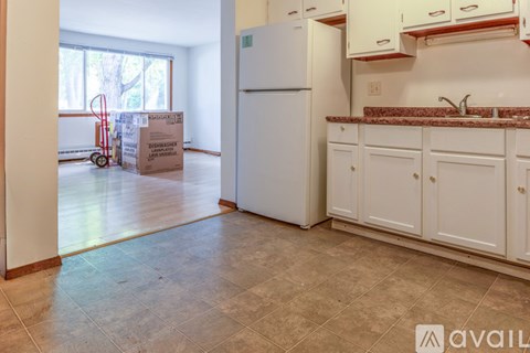 A kitchen with white appliances and cabinets is shown with a cardboard box and a red hand truck in the background.