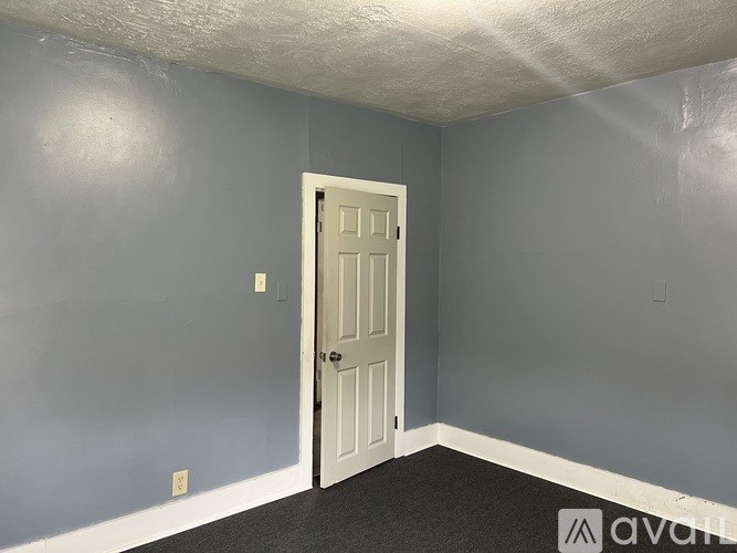 A room with a door and a wall with a few marks on it.