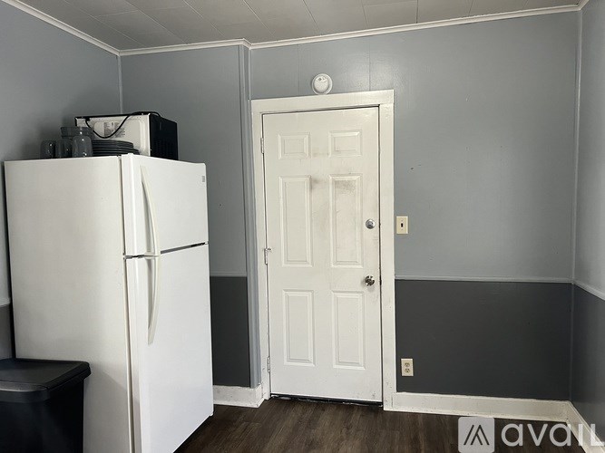 A white refrigerator is in a kitchen with a white door.