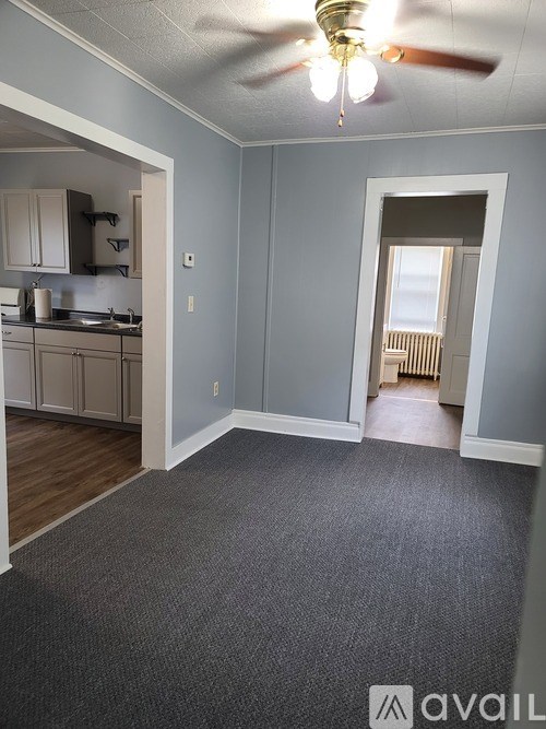 A room with a ceiling fan and a doorway leading to another room.