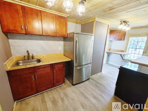 A kitchen with wooden cabinets and a stainless steel refrigerator.