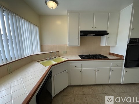 A kitchen with white cabinets and a black stove top.