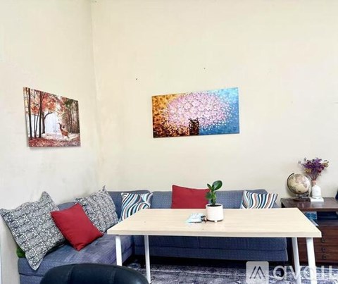 A living room with a couch, a table, and two pictures on the wall.