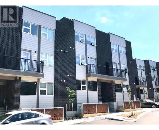 A modern apartment building with balconies and a car parked in front.