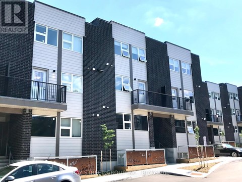 A modern apartment building with balconies and a car parked in front.