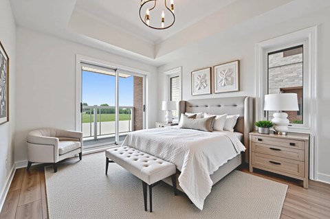 A bedroom with a large bed, a chair, and a window overlooking a grassy area.