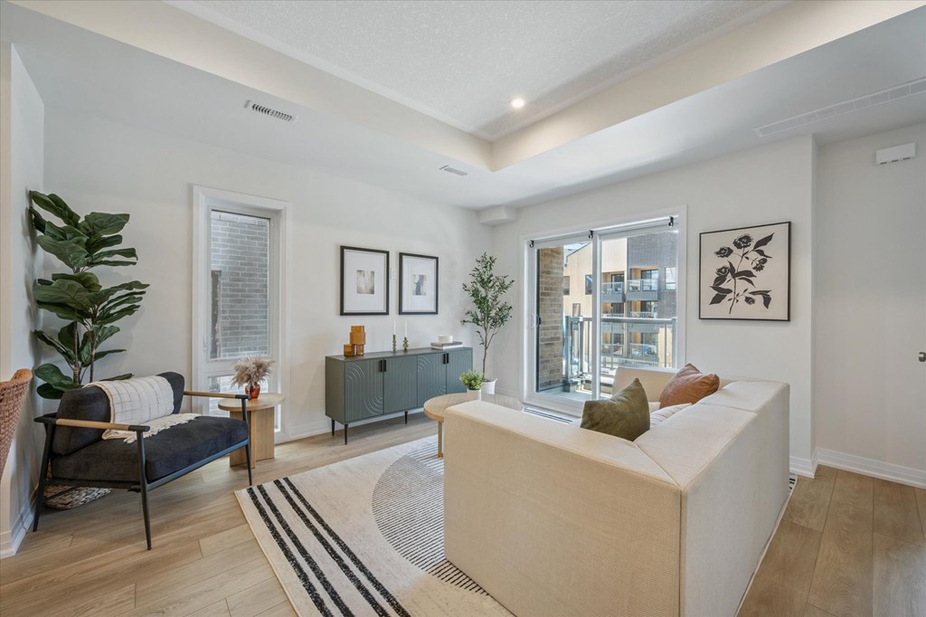 A living room with a sofa, a chair, a rug, and pictures on the wall.
