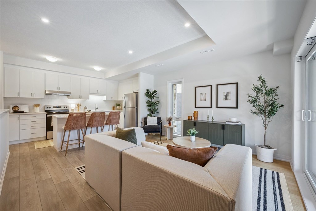 A modern living room with a sofa, chairs, and a kitchen area in the background.