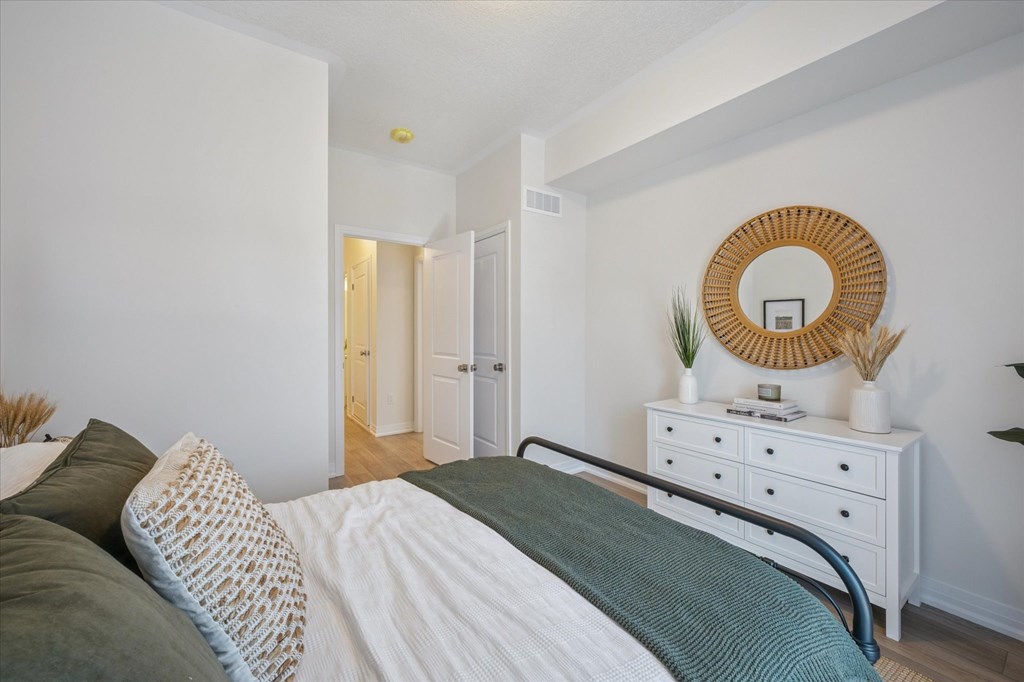 A bedroom with a bed, nightstand, and mirror.