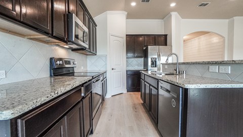 A kitchen with dark brown cabinets and a granite countertop.
