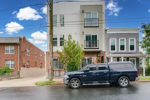 A blue SUV is parked in front of a modern apartment building.