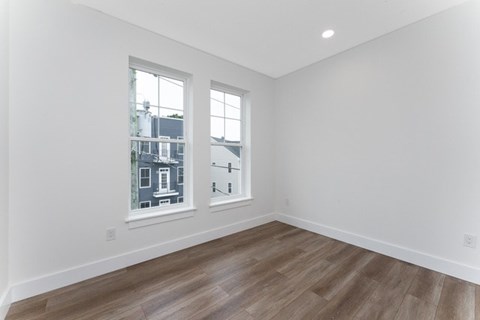 A room with a window showing a view of a house across the street.