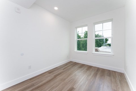 A room with a window and a wooden floor.