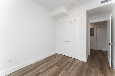 A room with a white door and a wooden floor.
