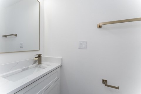 A white bathroom with a sink and a mirror.