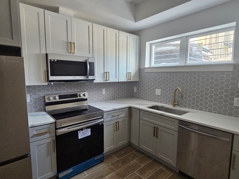 A kitchen with a black stove top oven and white cabinets.