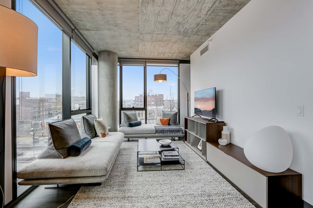 A modern living room with a large window and a grey sofa.