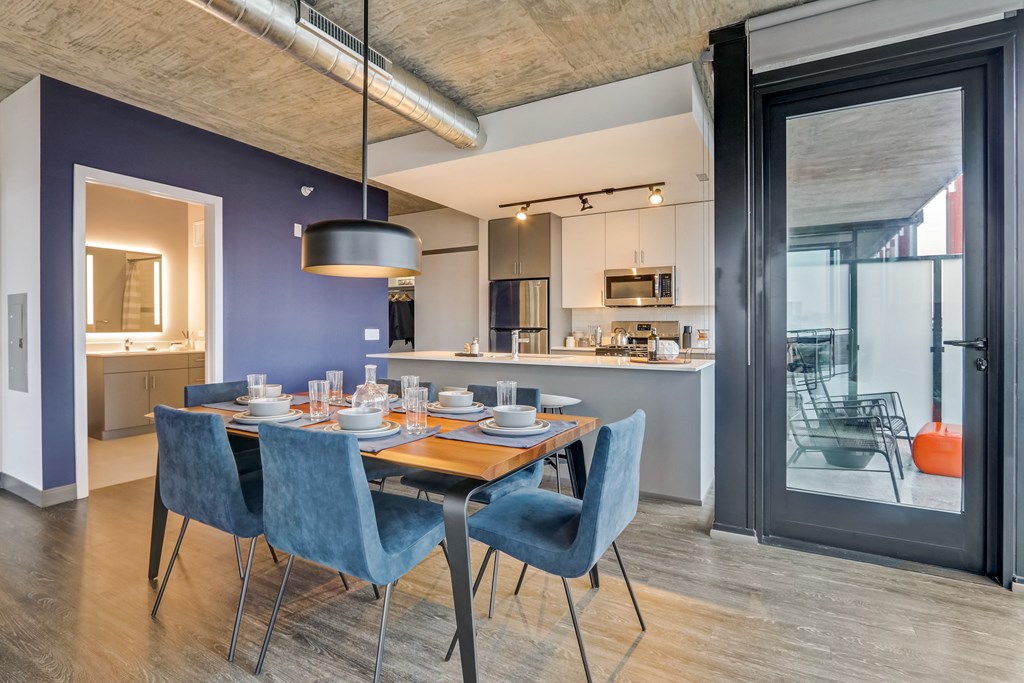 A modern kitchen with blue chairs and a dining table.