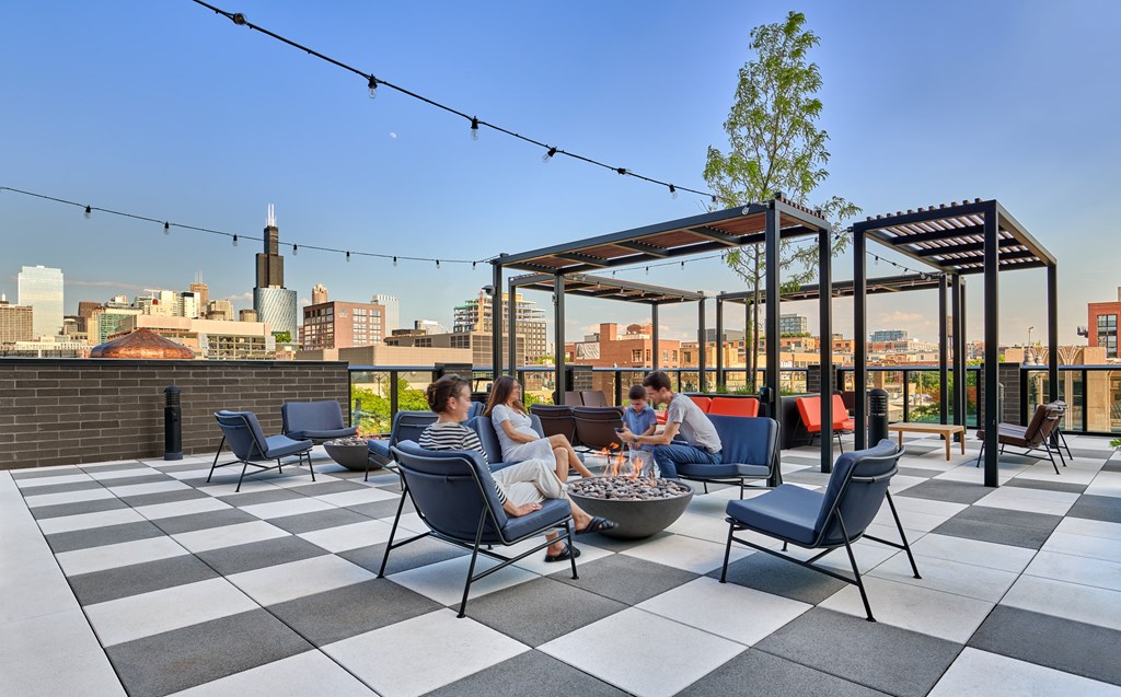 A group of people are sitting on a rooftop terrace with a view of the city.