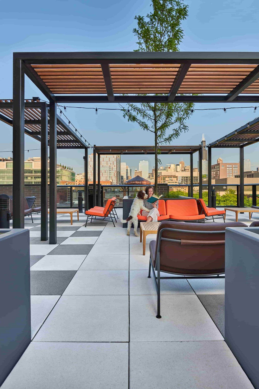 A woman is sitting on a chair under a pergola on a patio.