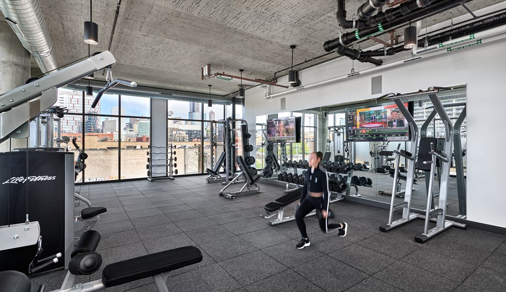 A person is working out in a gym with a view of the city.