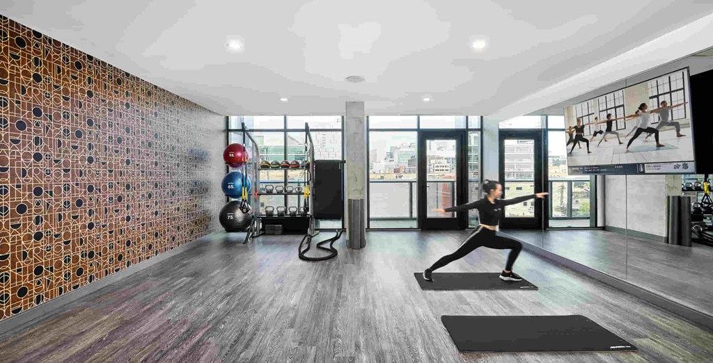 A gym with a woman exercising and a man working out.