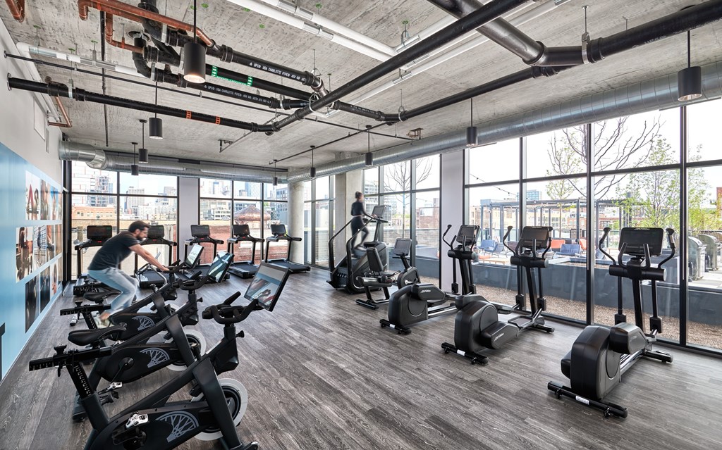 A man is working out on a stationary bike in a gym with multiple exercise bikes.