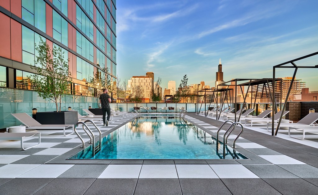 A man is walking on a rooftop pool deck.