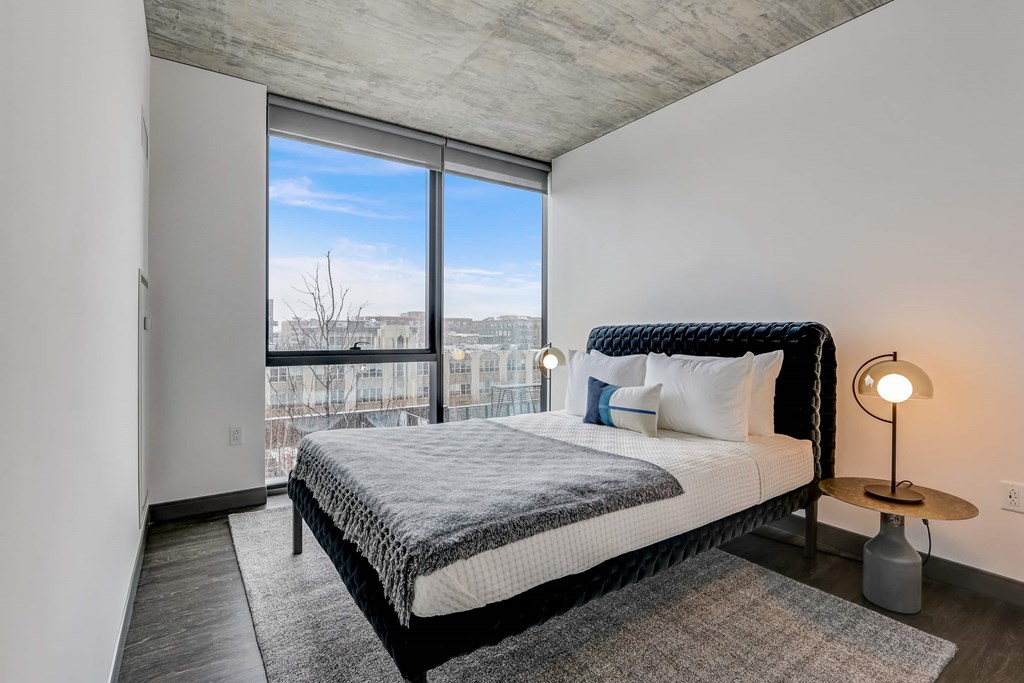 A bedroom with a large bed and a view of the city through the window.