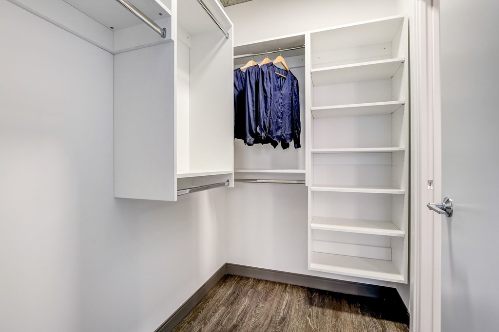 A white closet with clothes hanging and shelves.