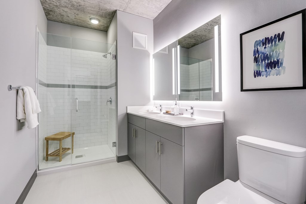A bathroom with a white toilet, a sink, and a shower.