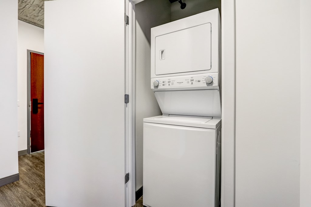 A white dishwasher is in a narrow space between a wall and a door.