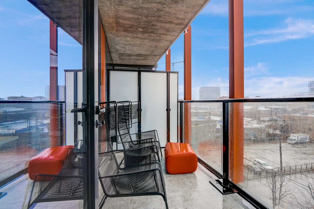 A balcony with a table and chairs overlooking a snowy landscape.