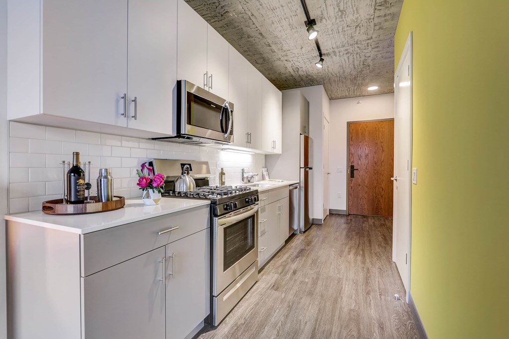 A kitchen with white cabinets and a stainless steel refrigerator.