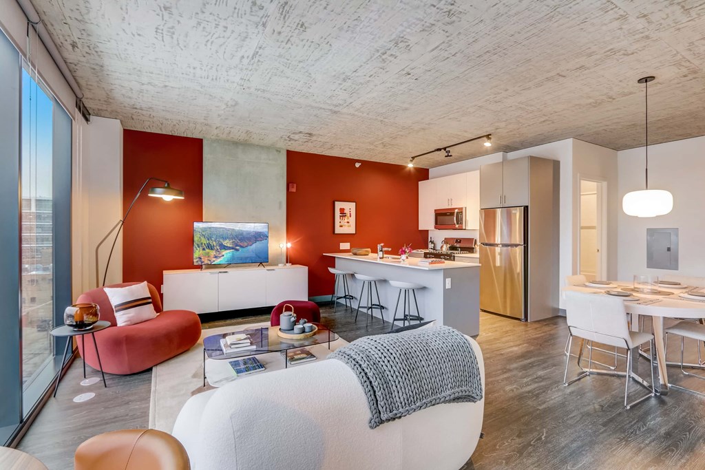 A modern living room with a white sofa and a red chair.