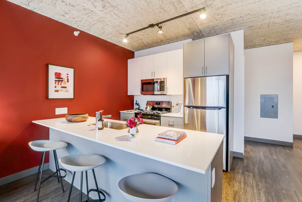 A kitchen with a red wall and white countertop.
