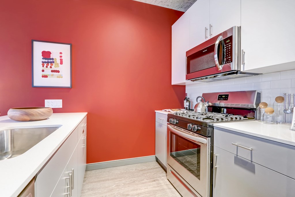 A kitchen with red walls and white cabinets.